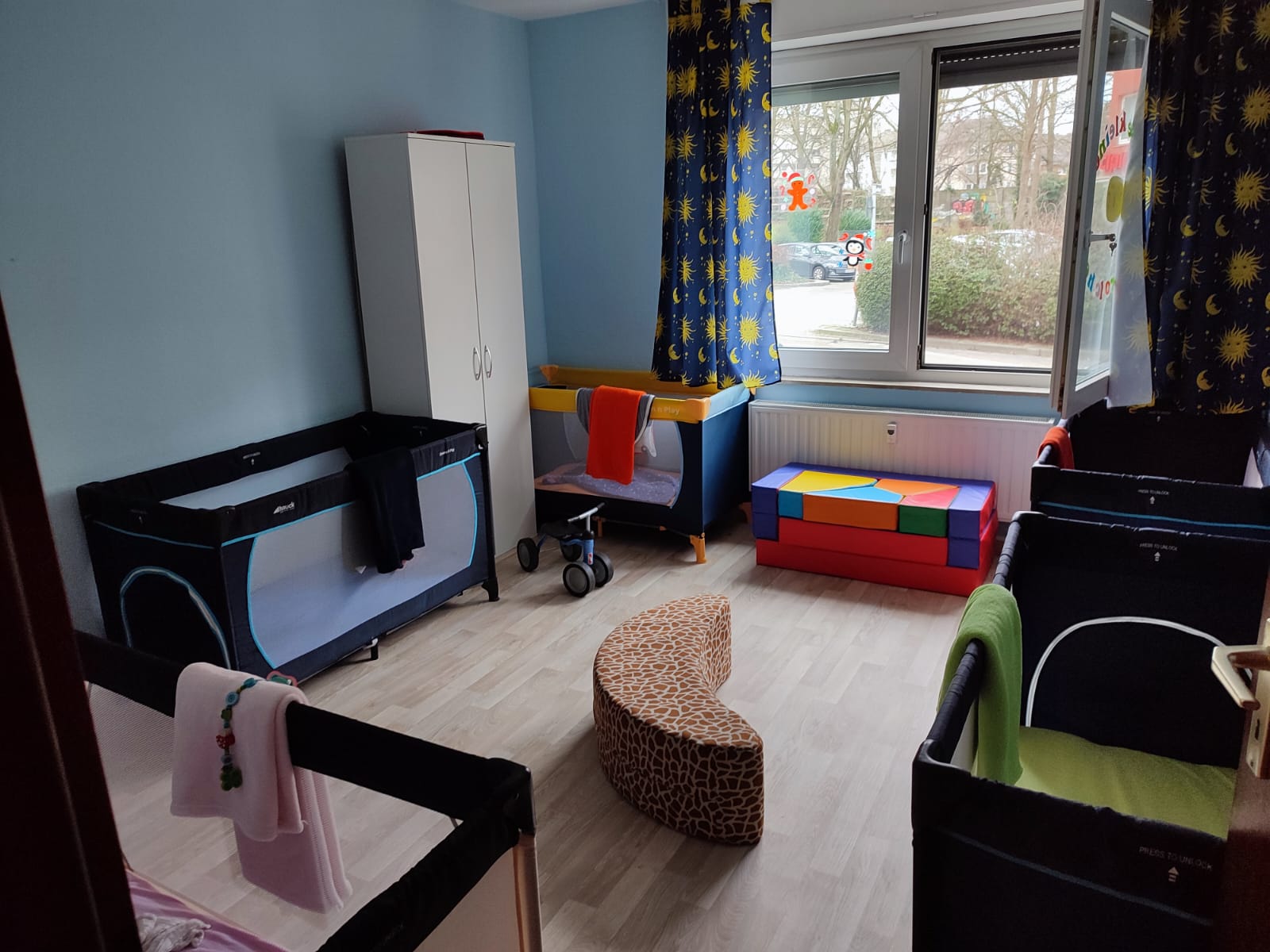 Ruhiger Schlafbereich mit Reisebetten und blauer Wand